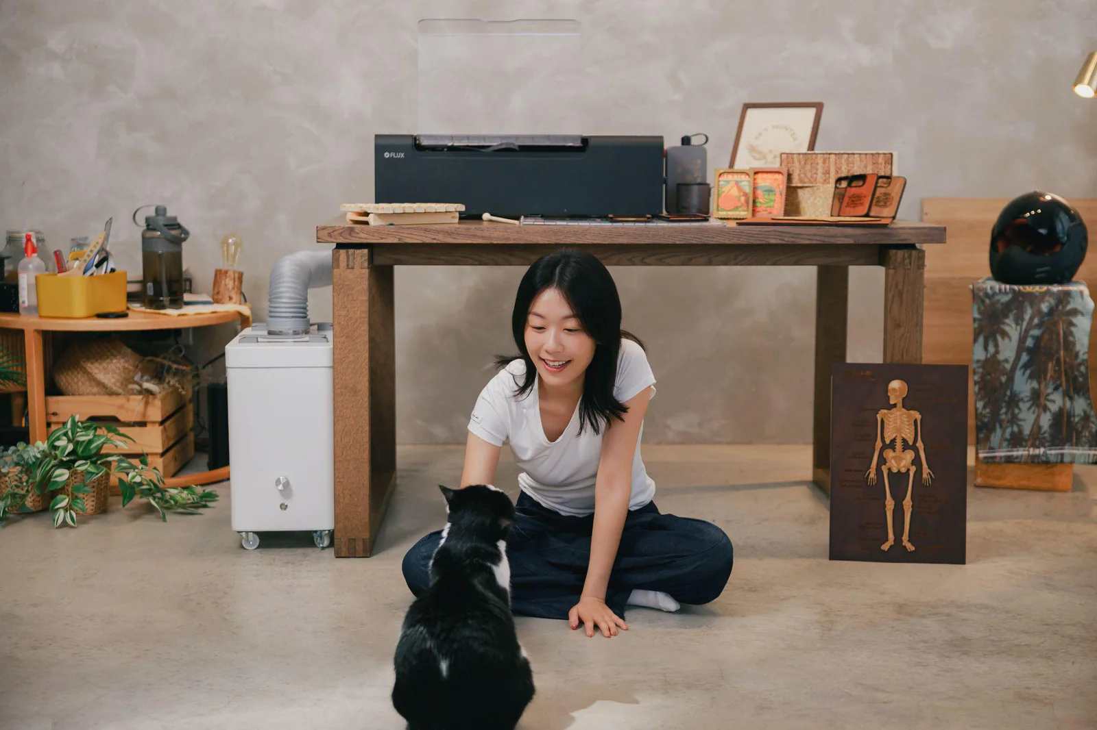 Creator seated beside beamo II in a compact home studio with finished laser-cut projects