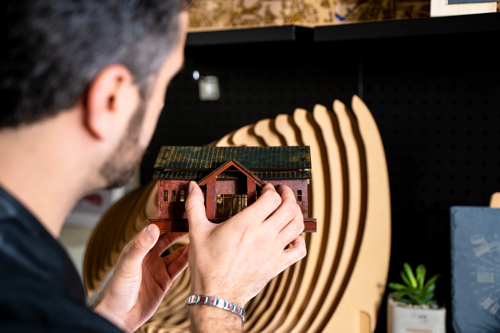 A maker assembling a laser-cut wooden architectural model by hand