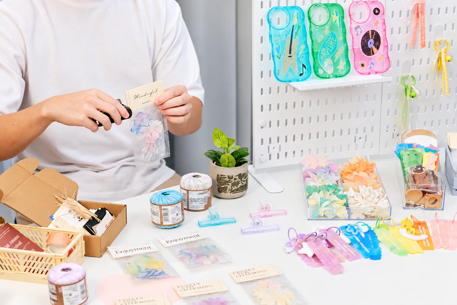 A maker packaging colorful handmade acrylic accessories at a craft table