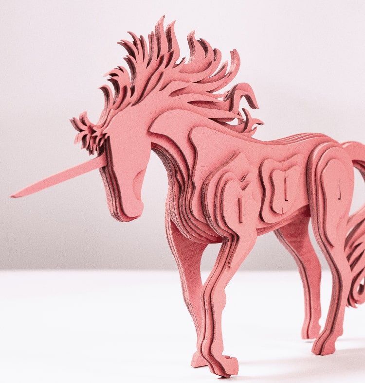 A pink unicorn made from stacked wooden plates laser cut to form a 3D version of a unicorn.
